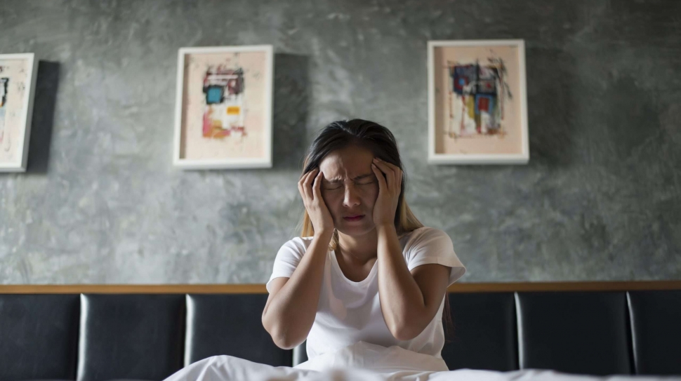 Depressed woman with headache hand holding her head on the bed