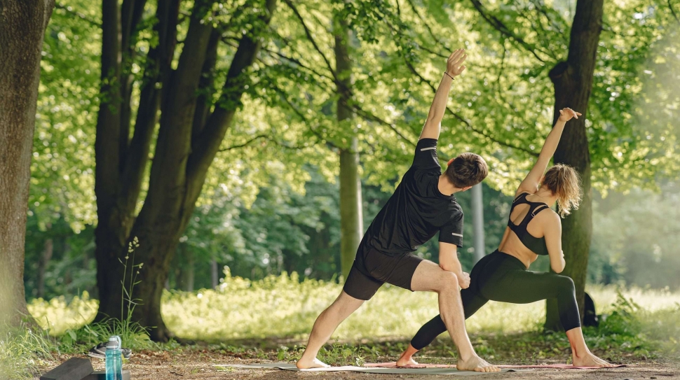 Young sportive couple doing yoga fitness . People in a summer park.