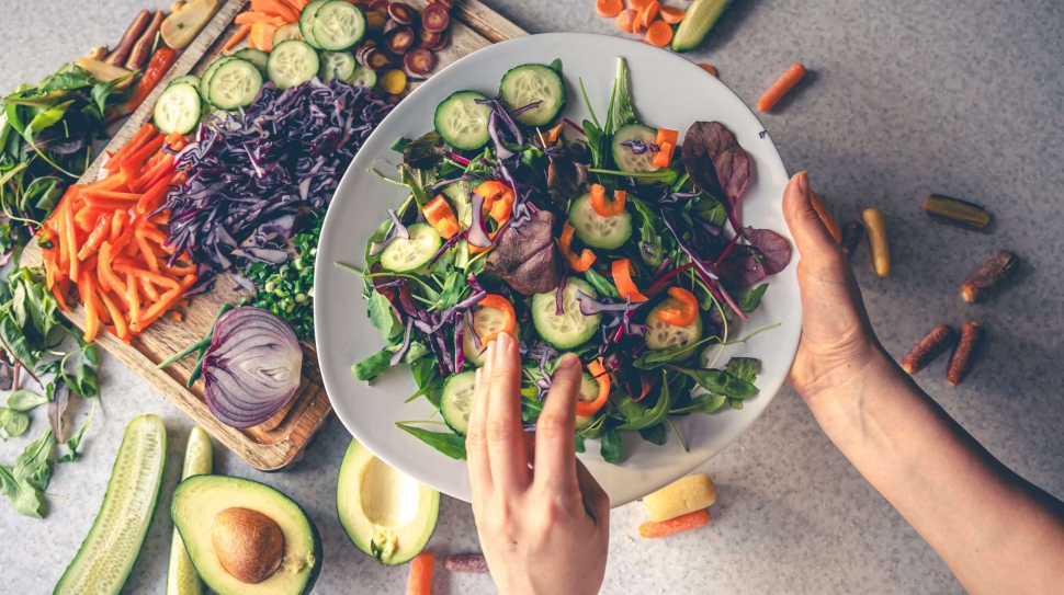 female-hands-holding-bowl-vegan-salad-with-fresh-vegetables-top-view
